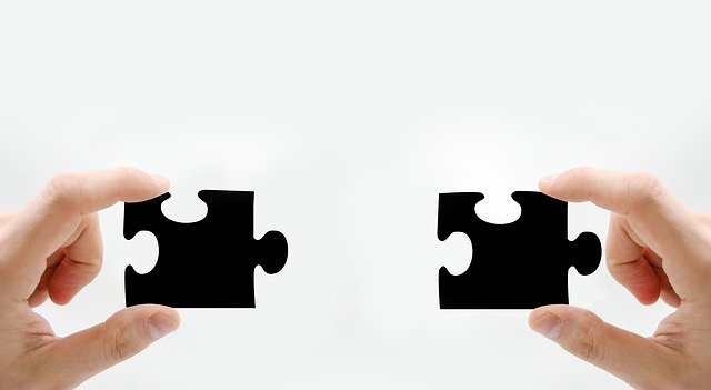Hands holding two puzzle pieces that fit together.